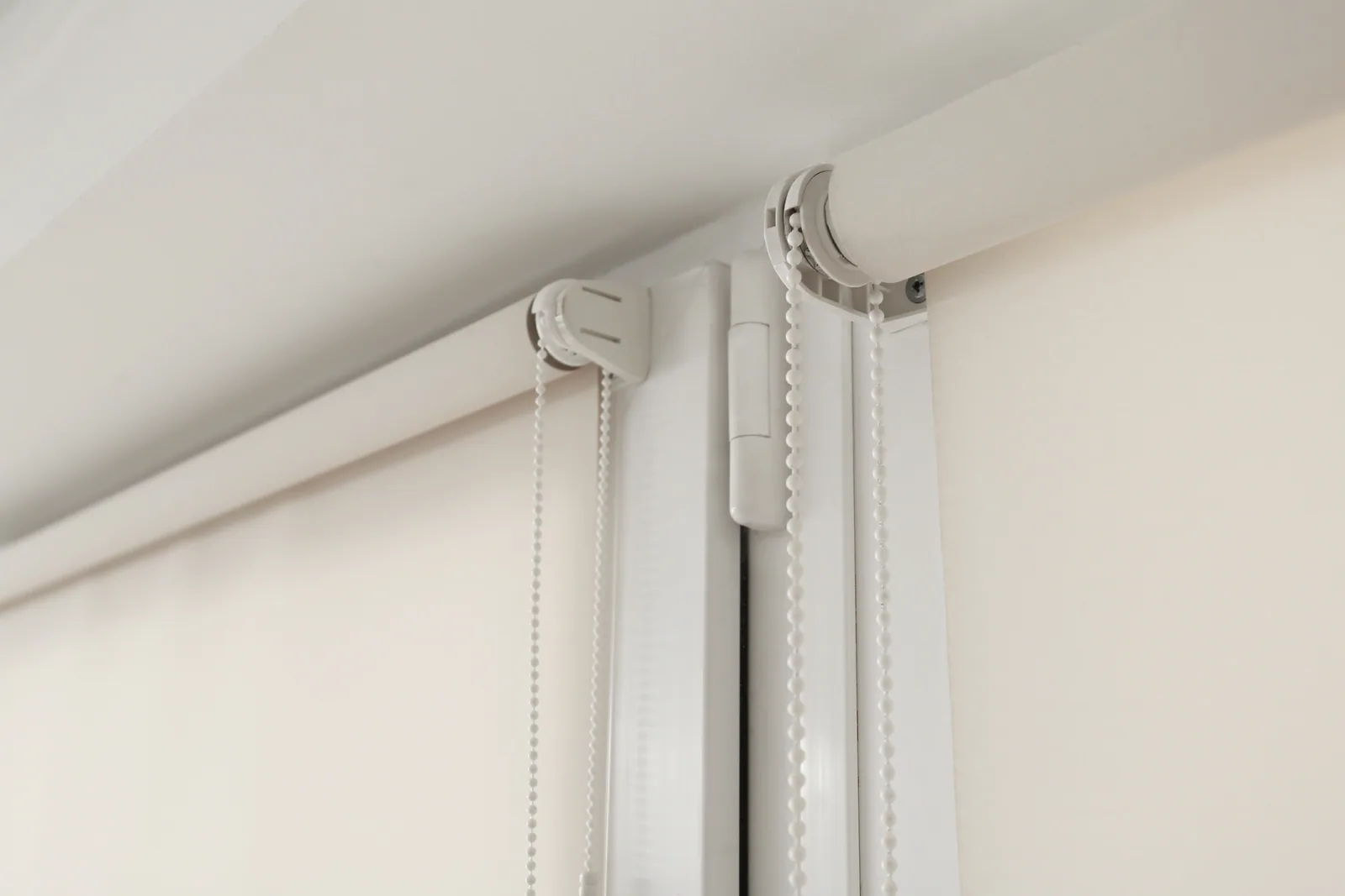 Close-up of cream roller blinds and their control chains